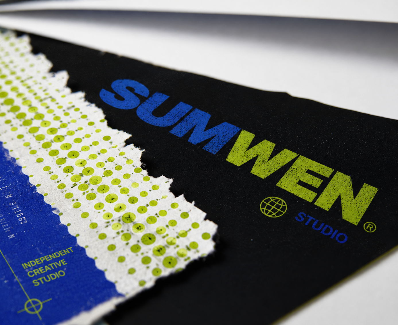 Close-up of a SUMWEN Studio screen print in electric blue and lime on black card